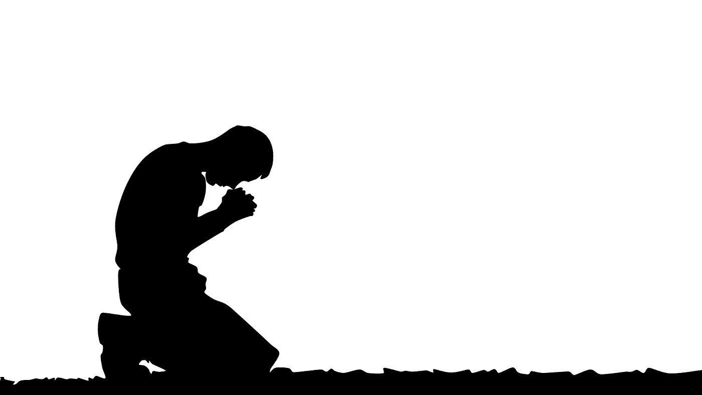 silhouette of a man kneeling and praying